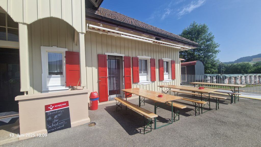 Aussenanstrich an Fassade mit hellen Holzflächen und roten Fensterläden