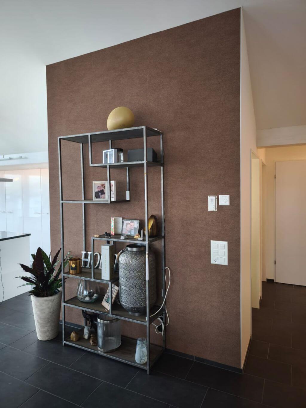 Moderne Akzentwand mit brauner Strukturtapete und dekorativem Regal in einem Wohnbereich.