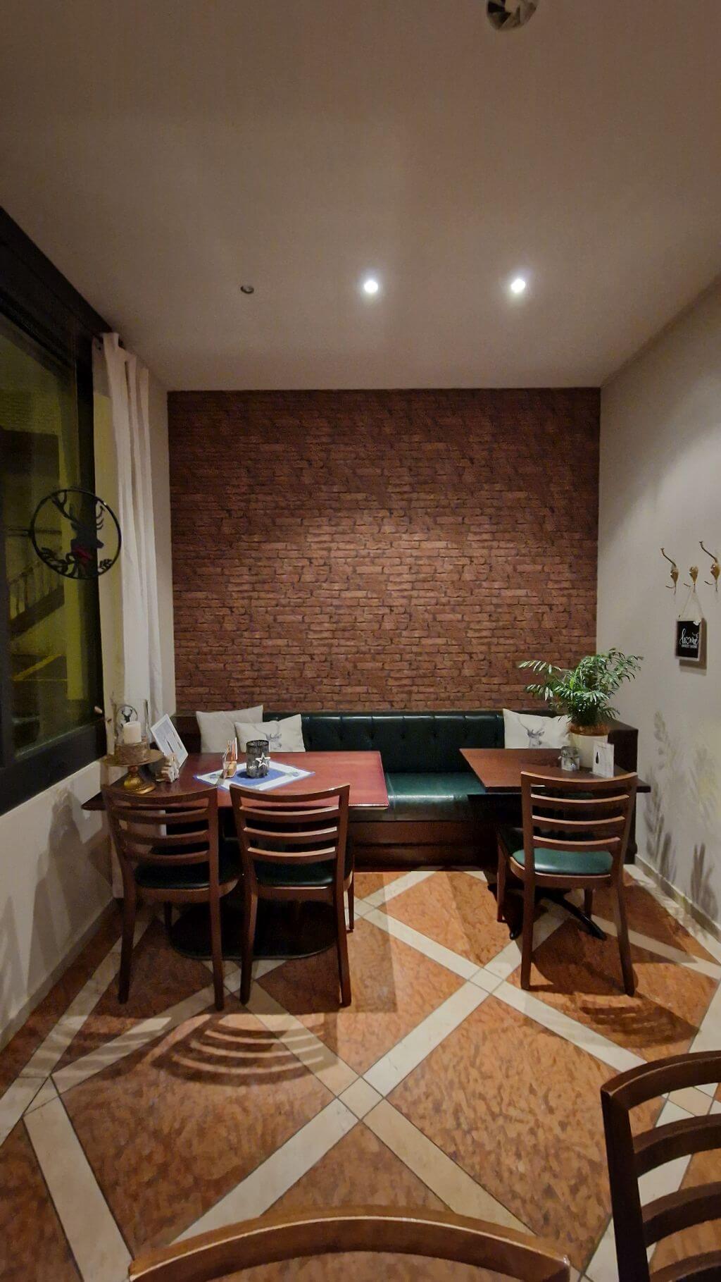 Akzentwand mit Tapete in Backsteinoptik in einem Gastronomiebereich mit Sitzbank und Tischen.
