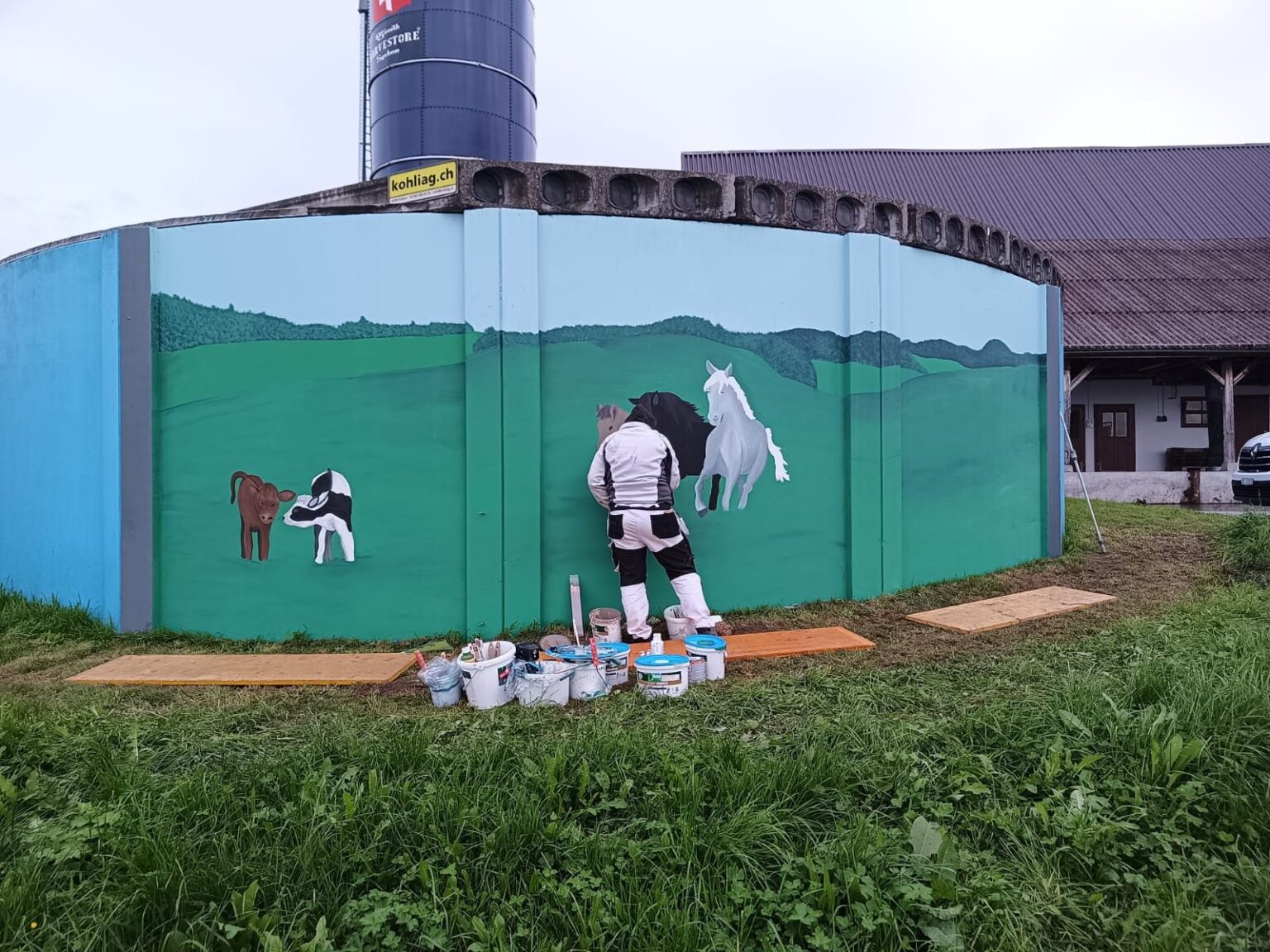 Malerin malt ein Wandbild an einem Silo